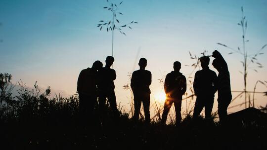 Silhuetter av ungdommer i solnedgang